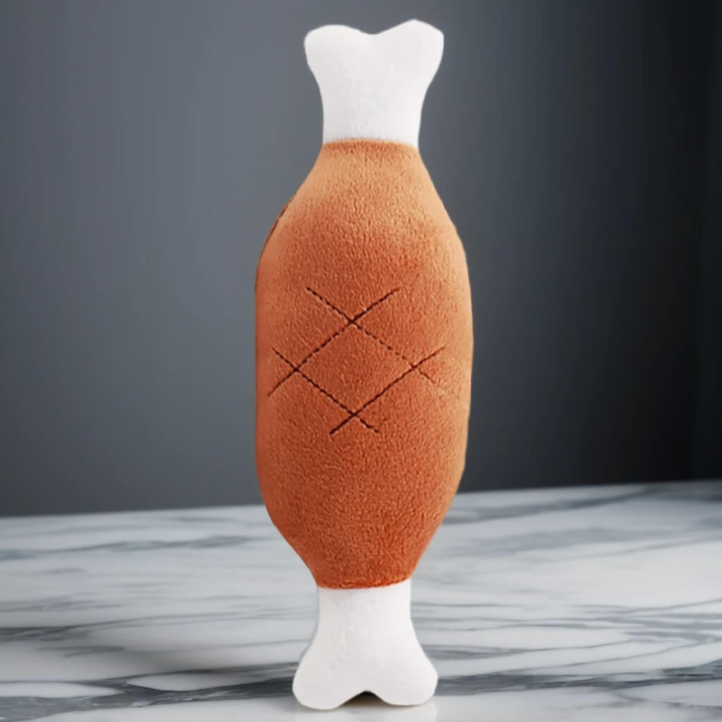 Jouet en peluche en forme de cuisse de viande pour chiens et chats. Matériau doux et durable, idéal pour le jeu interactif et la mastication.